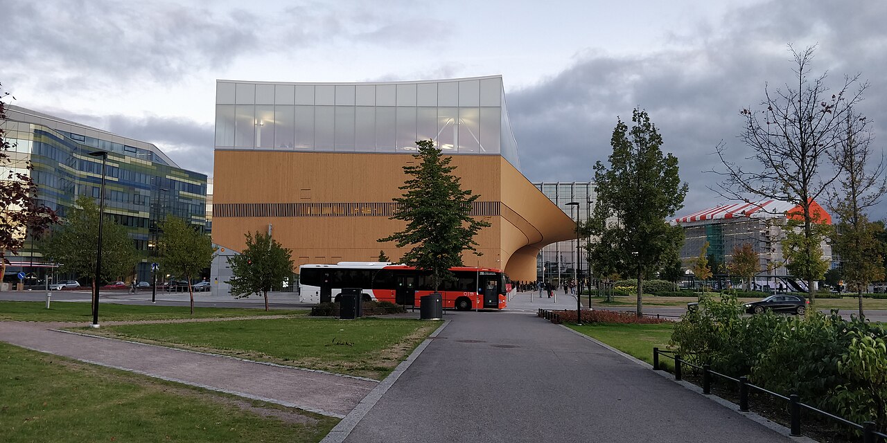Helsingin keskustakirjasto Oodi ja punainen bussi iltapäivän valossa
